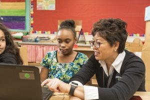 4-H stem educator shows a young girl something on the computer 