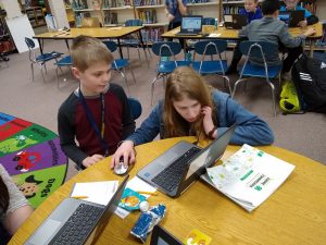 4-H members at a table completing an activity on the laptop