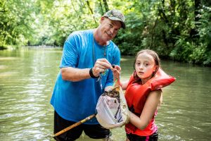 man and girl standing in creek with net