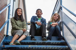 3 youth sitting on metal stairs