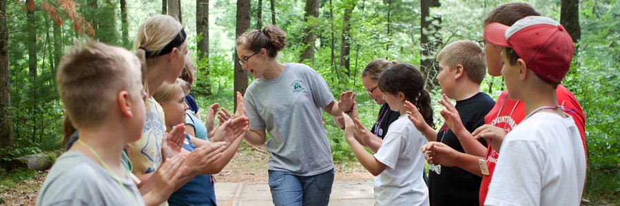 Youth at camp in the woods working with a camp councilor 