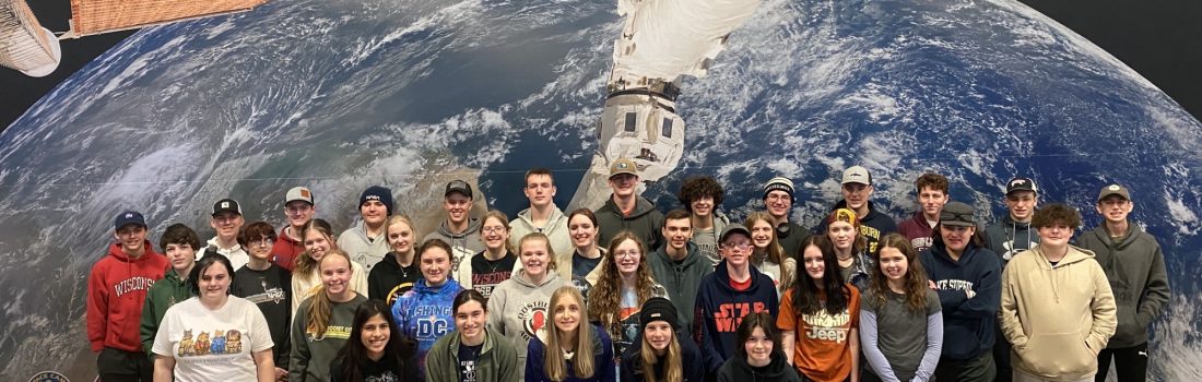 Academy delegates pose for a photo in front of a giant image of the earth at the U.S. Space & Rocket Center