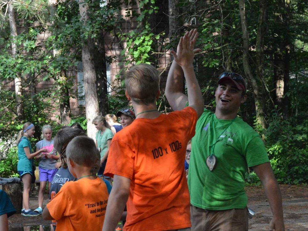 Camper and camp counselor high five