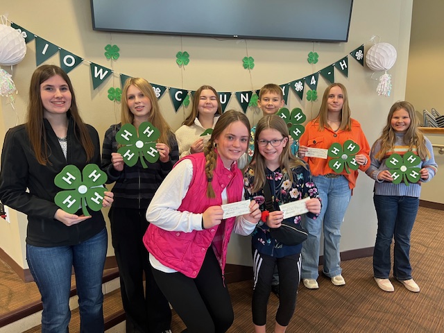 Iowa County 4-H youth members pose for a picture including 4-H clovers and their awards.