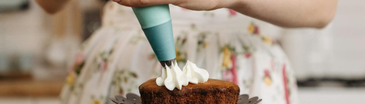 Young person decorating a small cake with frosting