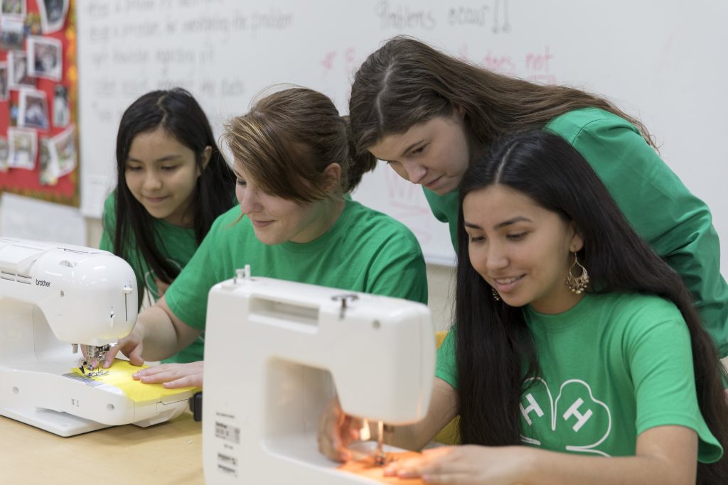 Two youth using sewing machines while others look on