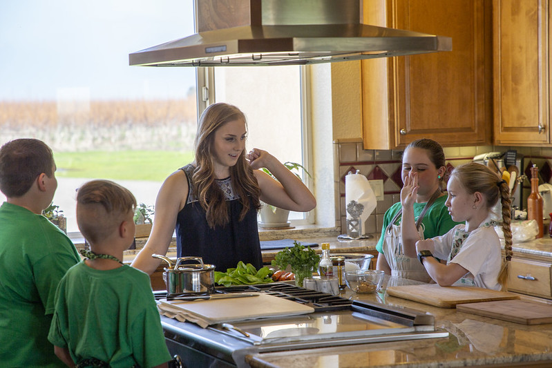 Teen leading a cooking workshop for 4 younger children
