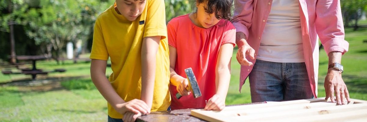 2 youth in a woodworking project with an adult helper