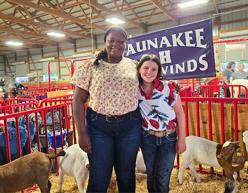 Two 4-H youth standing together at the fair with their goat projects