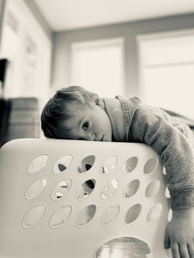 A young child laying on the bottom of a laundry basket.