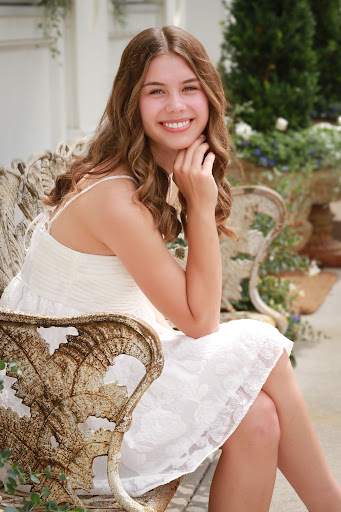 A young person in a white dress sitting on a bench.