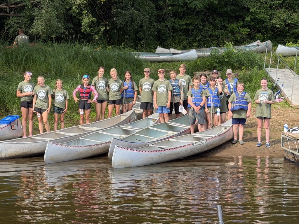Youth at Outpost Camp gather by canoes to set out on the water.